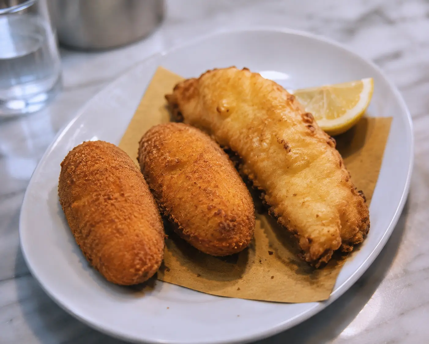 Supplì e filetto di baccalà fritti, serviti su carta paglia